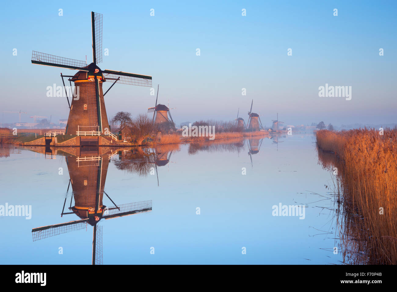 Traditional Dutch windmills reflected in perfectly still water on a cold morning in winter, at the Kinderdijk in The Netherlands Stock Photo