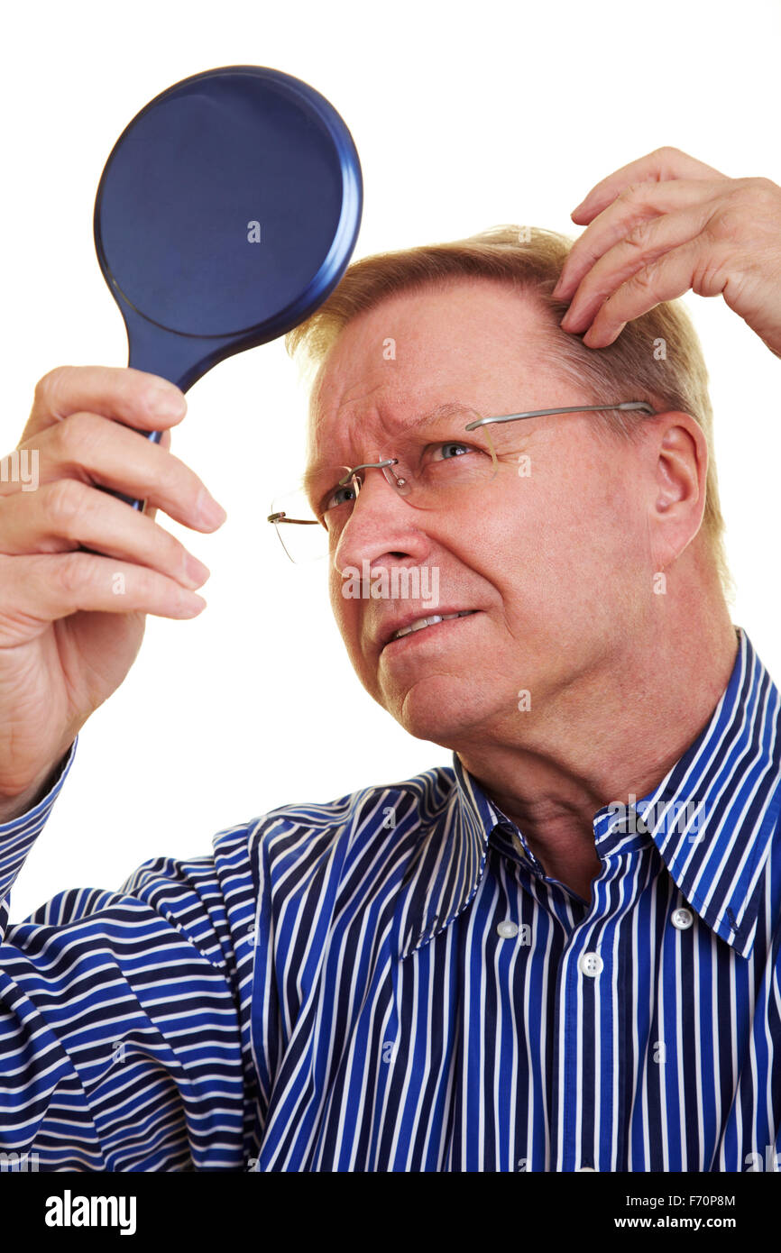 Eldery man watching his receding hair line in mirror Stock Photo