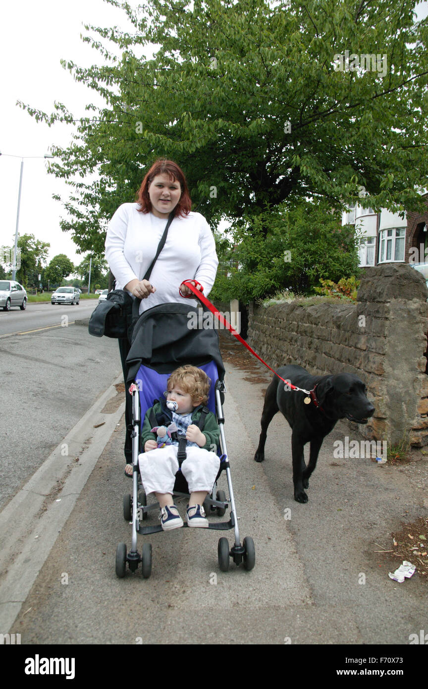 Mother with her baby son in his buggy out walking the pet dog Stock