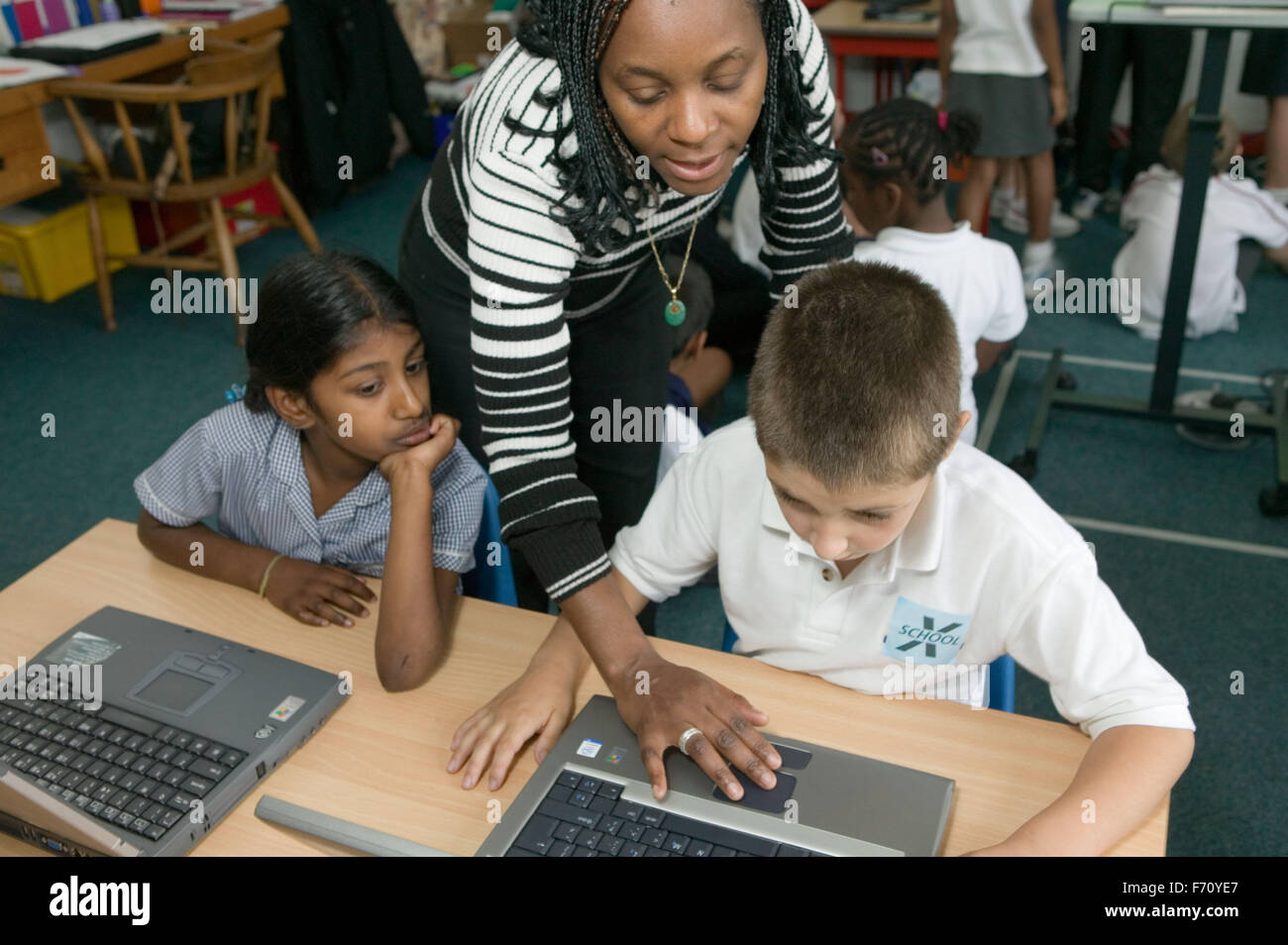 Teacher showing school children how to use computers in classroom Stock ...
