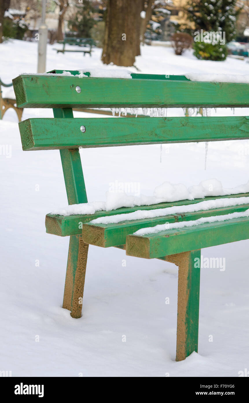 Snow and ice covered bench in a park Stock Photo