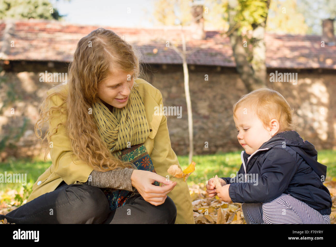 Blonde mom plays with her sweet one year old daughter in the park Stock Photo