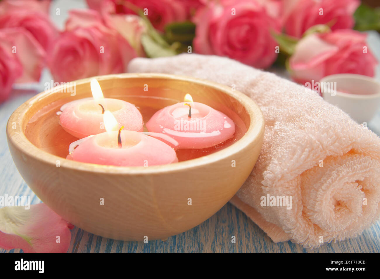 Fresh bright pink roses, petals, candle, and towel in a spa Stock