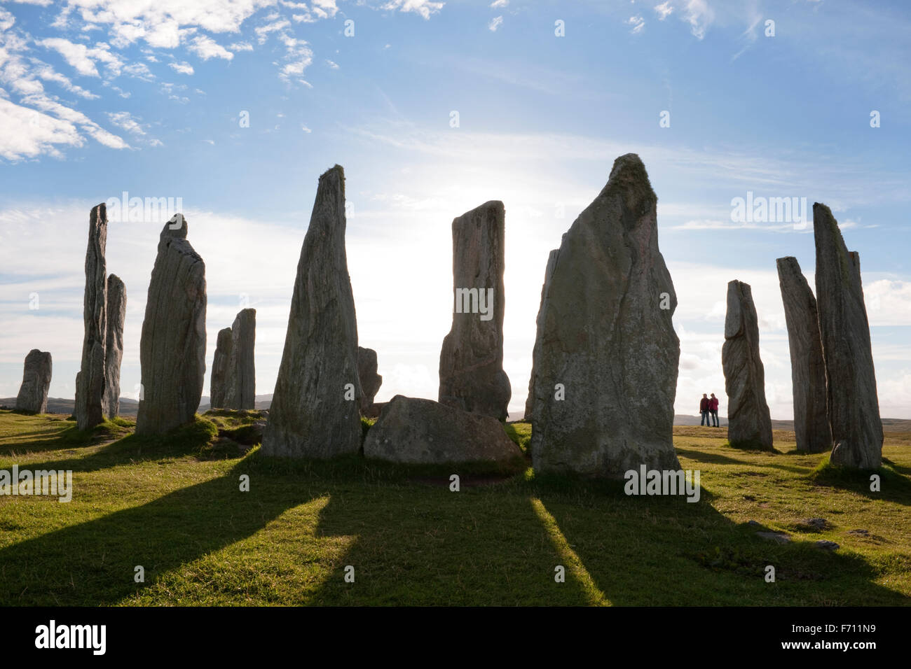Looking west at the centre of the Callanish (Calanais) Standing Stones prehistoric monument. Isle of lewis, Scotland; two people in silhouette. Stock Photo