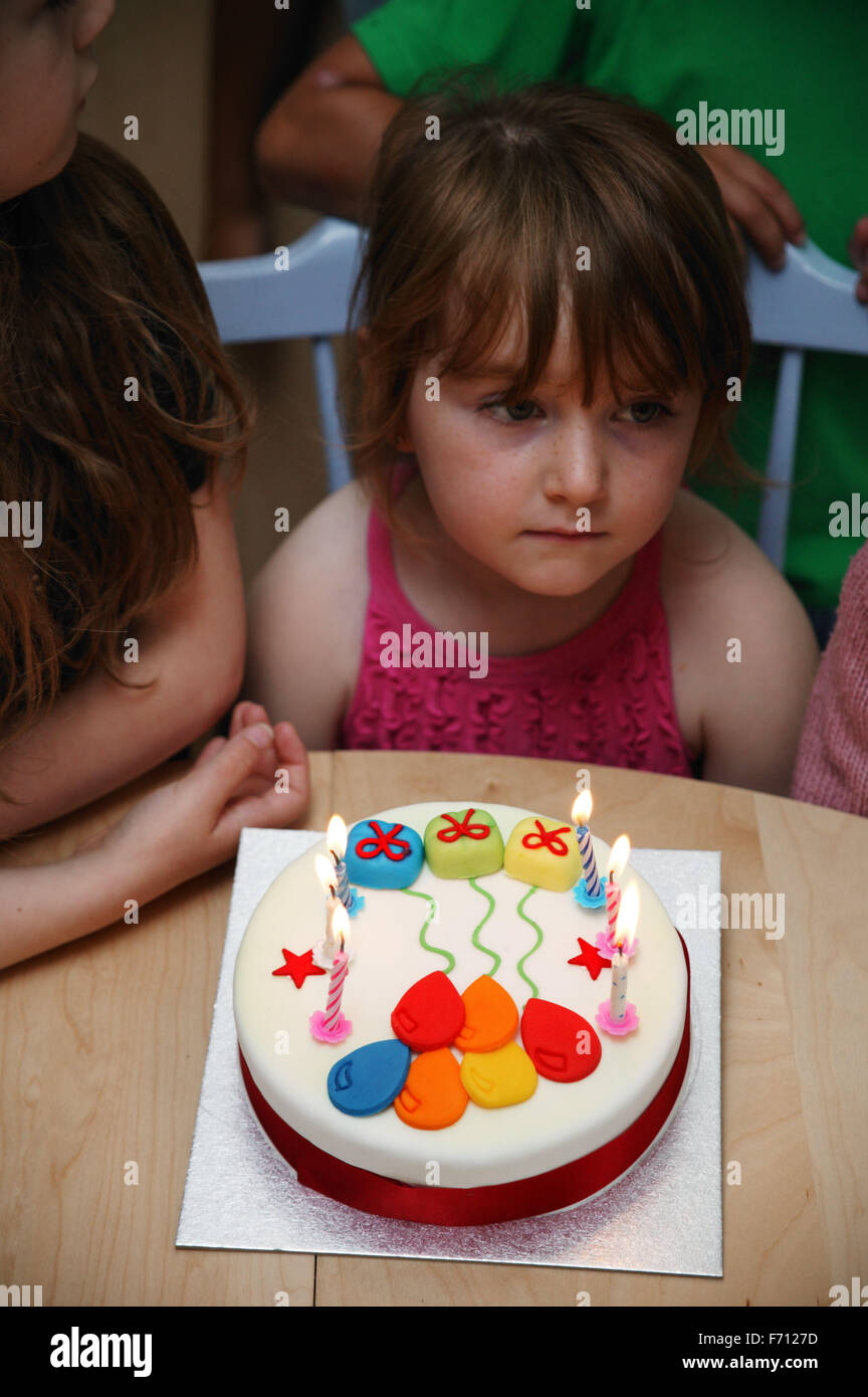 Young girl waiting to blow out candles on her birthday cake Stock Photo