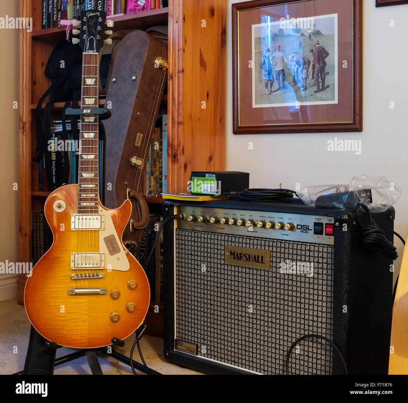 2015. A 1958 Gibson Les Paul guitar on it's stand next to a Marshall tube amplifier. The guitar's case in the background. Stock Photo