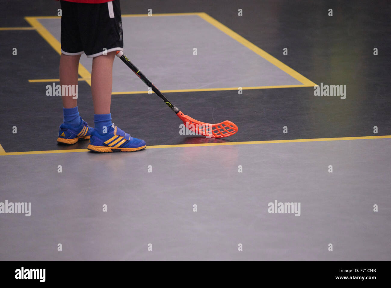 Children boys schoolchildren playing floorball (floor hockey) match in school gym  sport hall with plastic hockey sticks Stock Photo