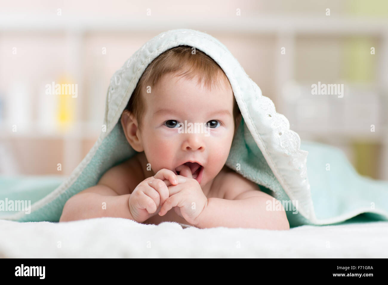 Baby kid under towel after shower sucking on his finger Stock Photo