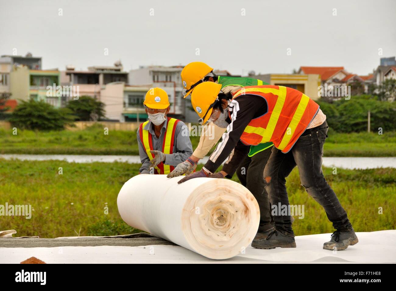 Vietnamese construction workers apply plastic sheeting during Dioxin remediation efforts of contaminated land around the airport January 22, 2013 in Da Nang City, Vietnam. Dioxin is an extremely hazardous chemical that was used in Agent Orange by the U.S. during the Vietnam war. Stock Photo