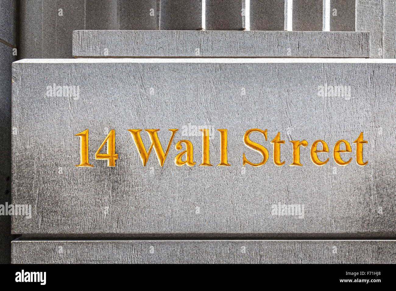New York, USA - September 13, 2015: Wall Street golden inscription on a building gray stone wall. Stock Photo