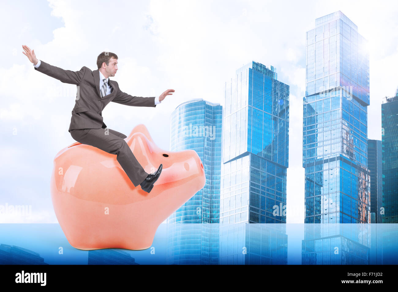 Man sitting on white piggy bank and city Stock Photo - Alamy