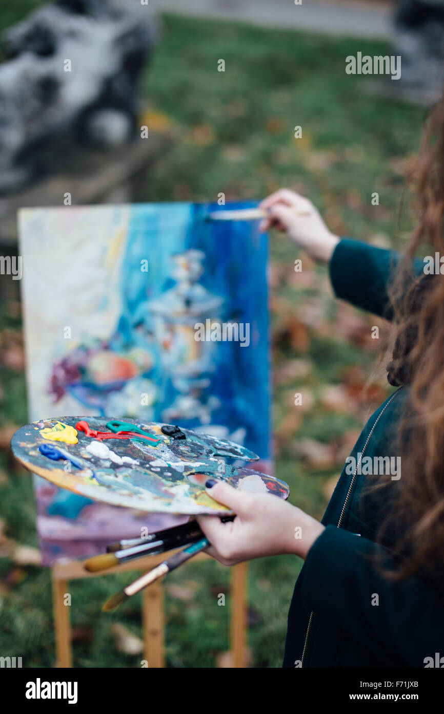 Young woman drawing in easel on the park background Stock Photo - Alamy