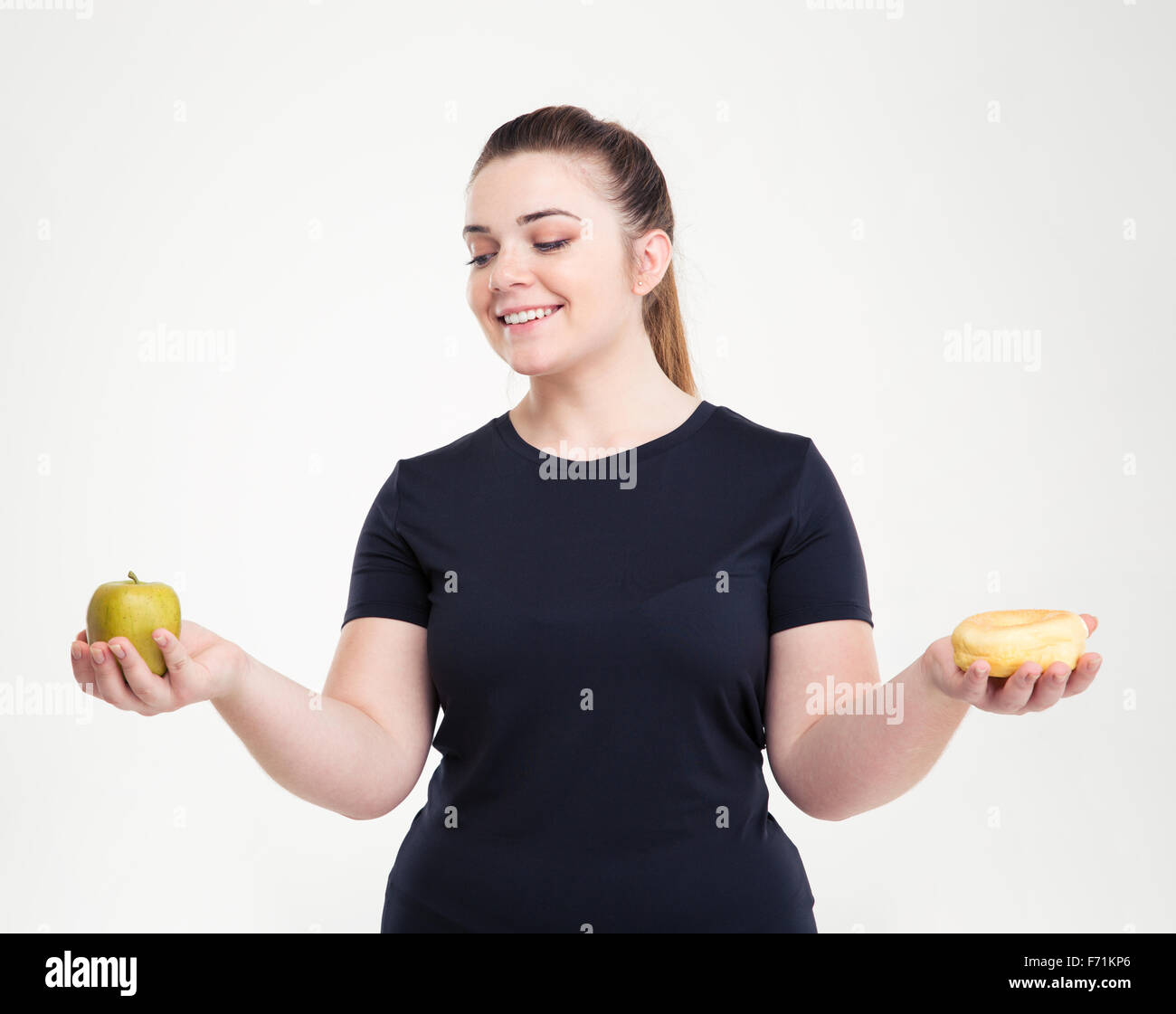 Portrait of a happy fat woman choosing between donut and apple isolated on a white background Stock Photo
