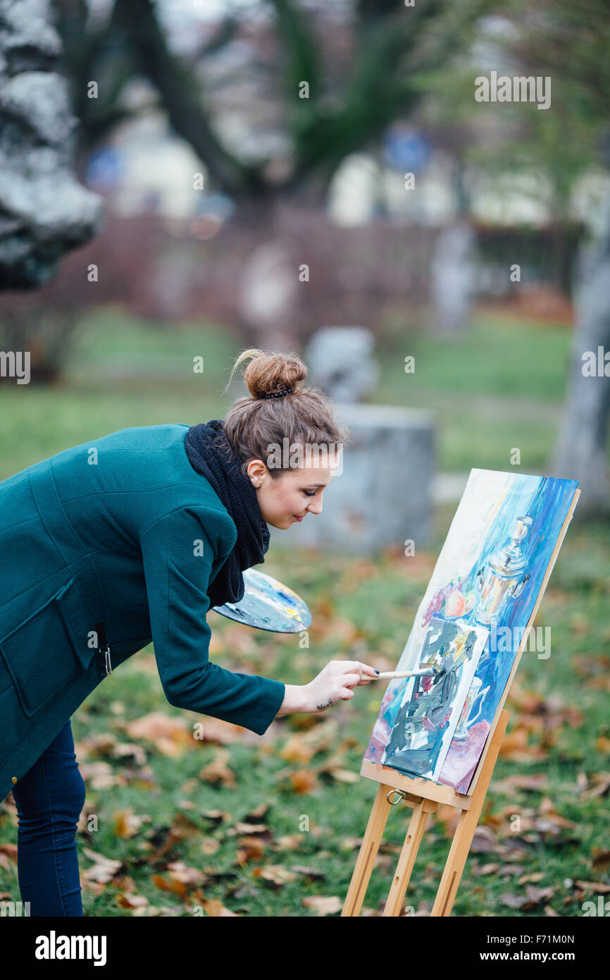 Young woman drawing in easel on the park background Stock Photo - Alamy