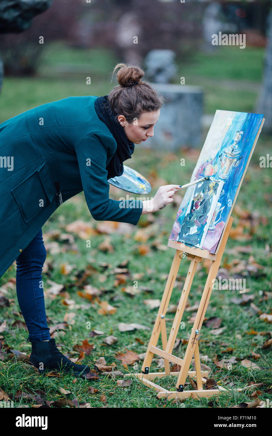 Young woman drawing in easel on the park background Stock Photo - Alamy