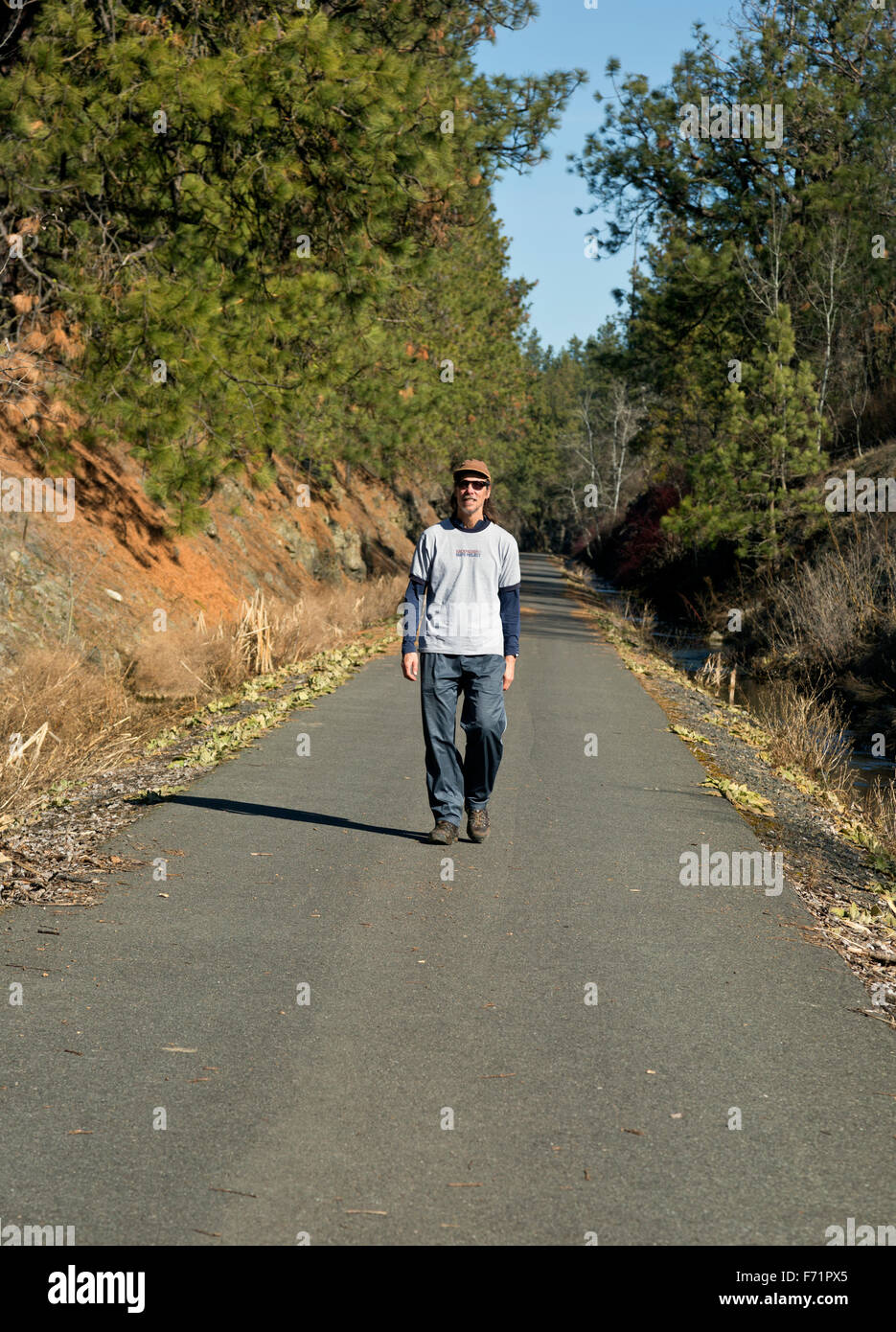 WASHINGTON - Hiker on a paved section of the Columbia Plateau Trail, an old railroad grade, near the Cheney Trailhead. Stock Photo