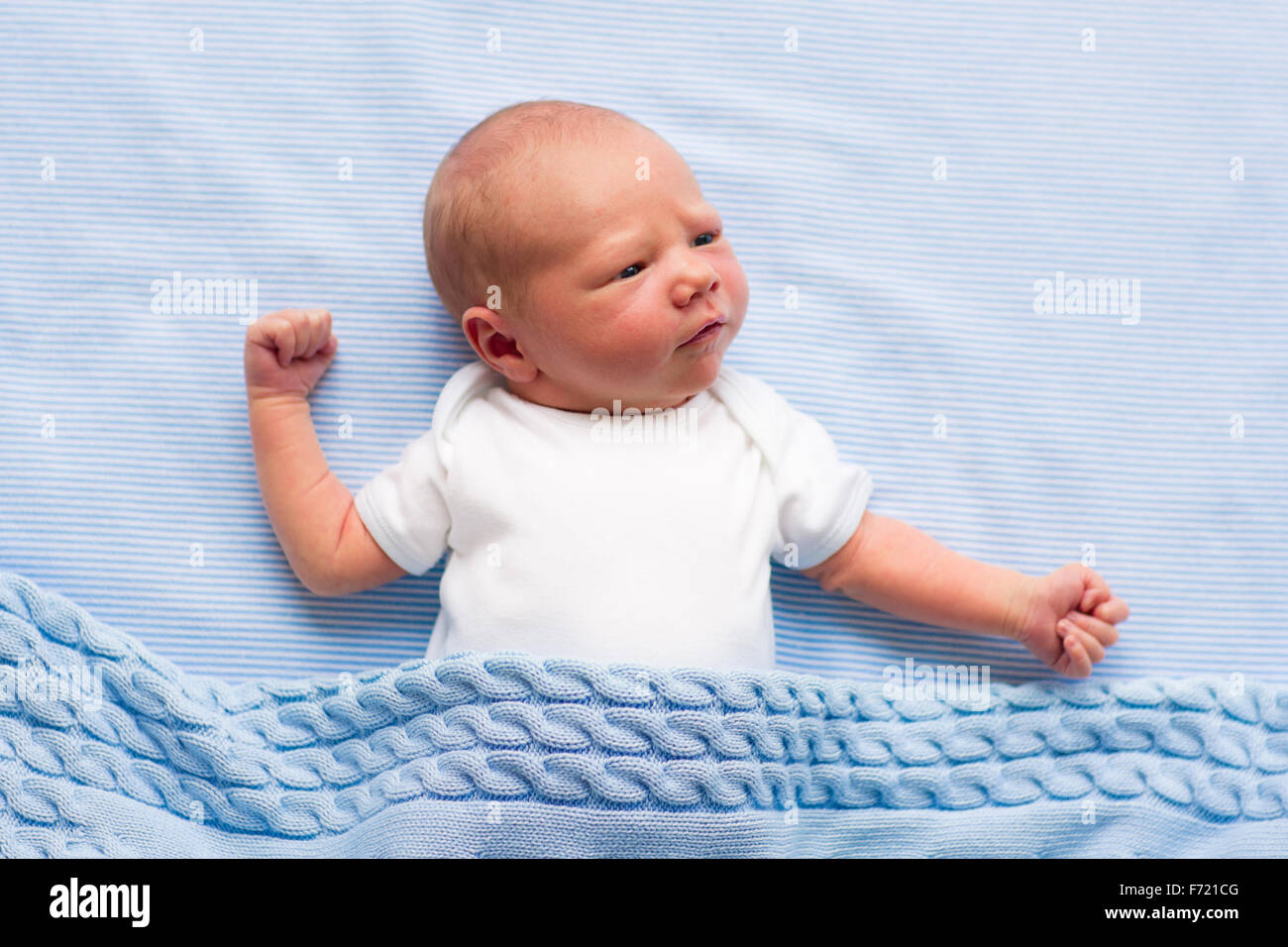 Newborn baby boy in bed. New born child sleeping under a blue knitted