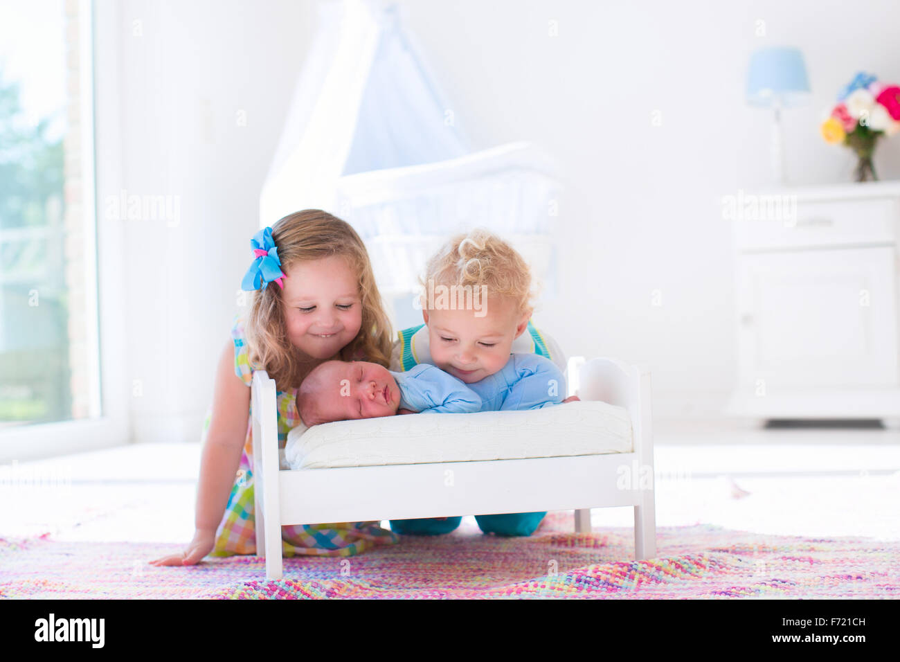 Cute little boy and girl kissing newborn brother. Toddler kids meet new