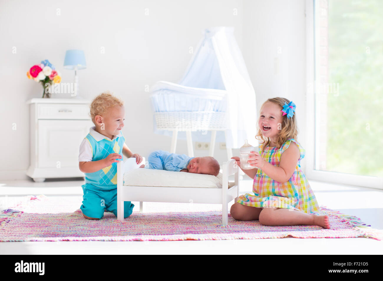 Cute little boy and girl kissing newborn brother. Toddler kids meet new