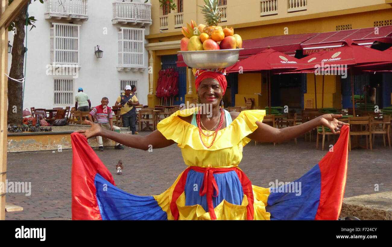 Caribbean woman in colorful dress with fruit basket on head in