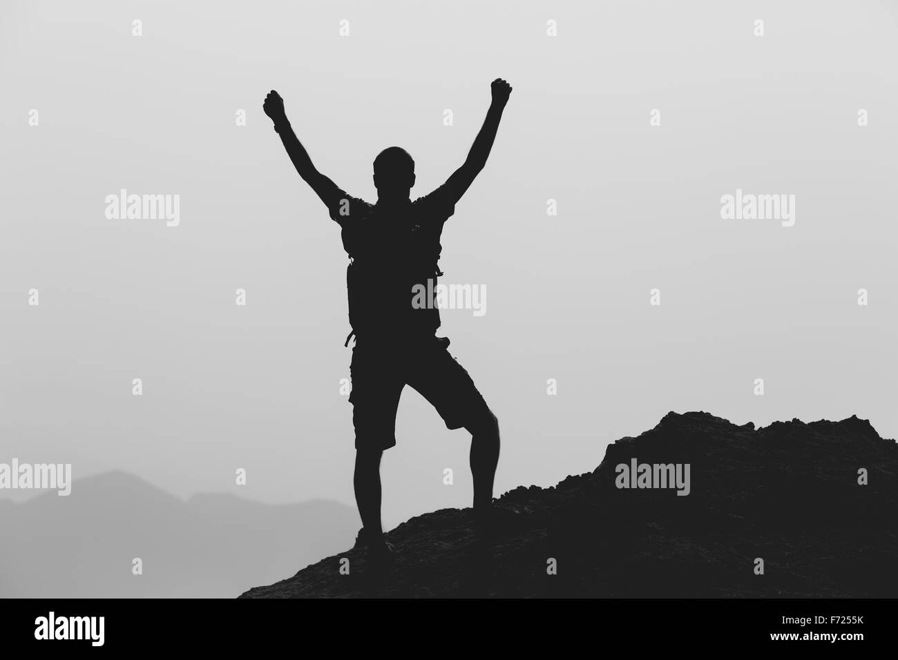 Success achievement climbing or hiking accomplishment business concept with man celebrating with arms up, raised outstretched. Stock Photo