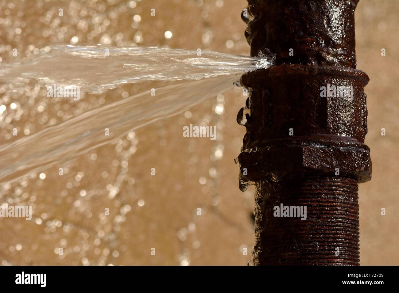 Rusty burst pipe in Baku Botanic Garden spraying water Stock Photo