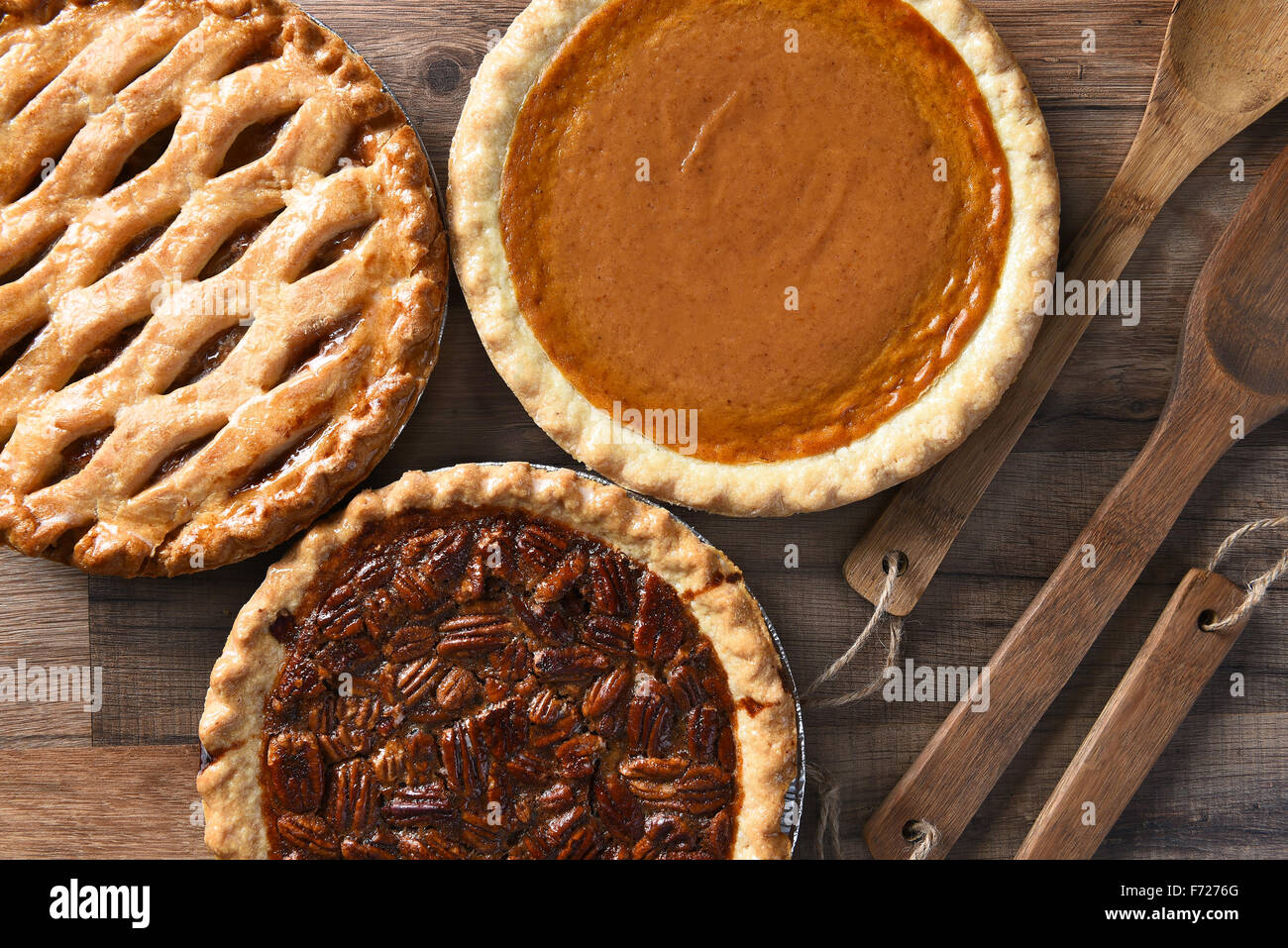 Overhead view of three pies for a Thanksgiving Holiday feast. Pecan, Apple and Pumpkin in horizontal format on wood table Stock Photo