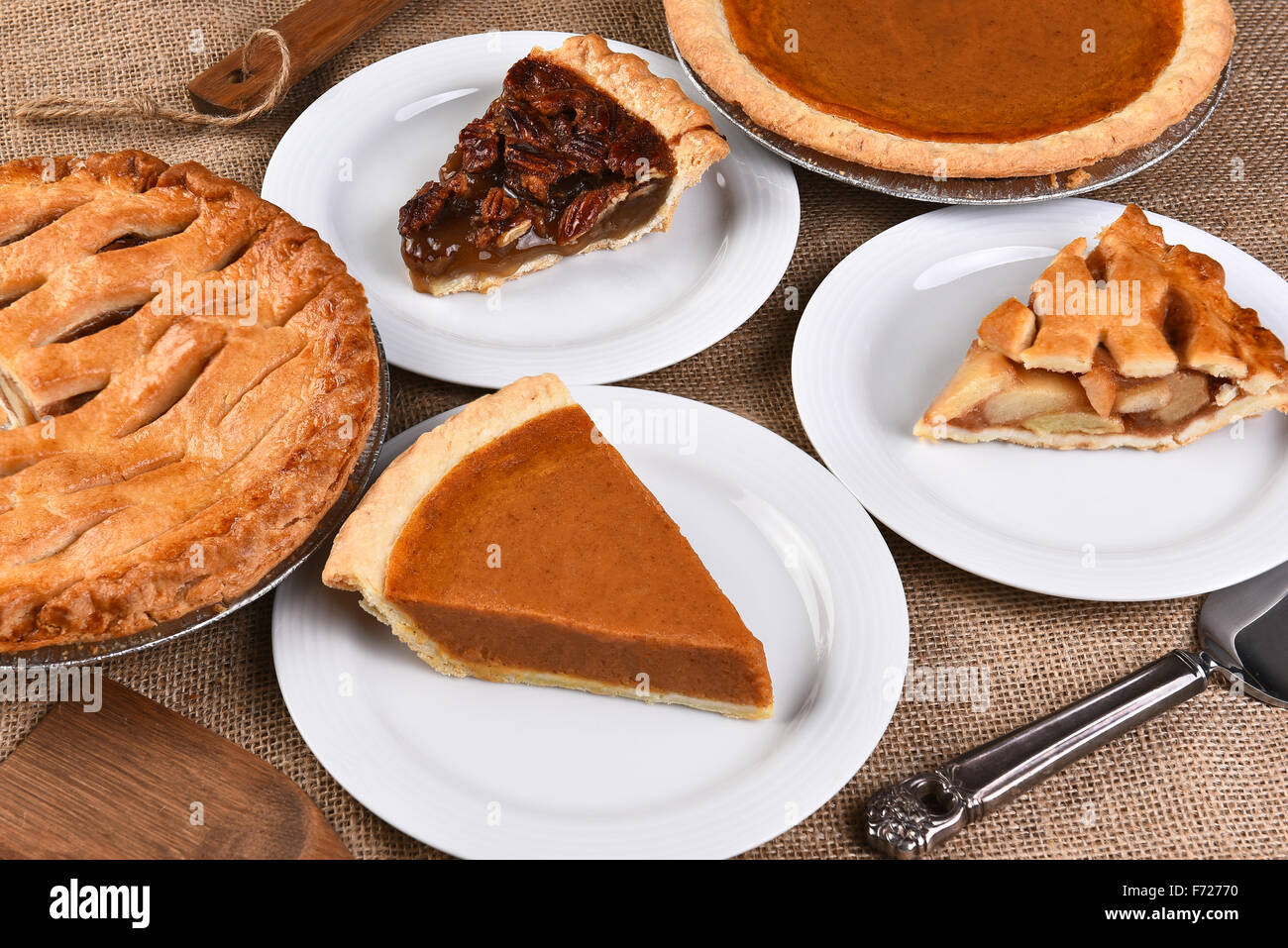 High angle view of whole pies and plates with slices. Traditional Thanksgiving desserts include, Pecan Pie, Apple Pie and Pumpki Stock Photo
