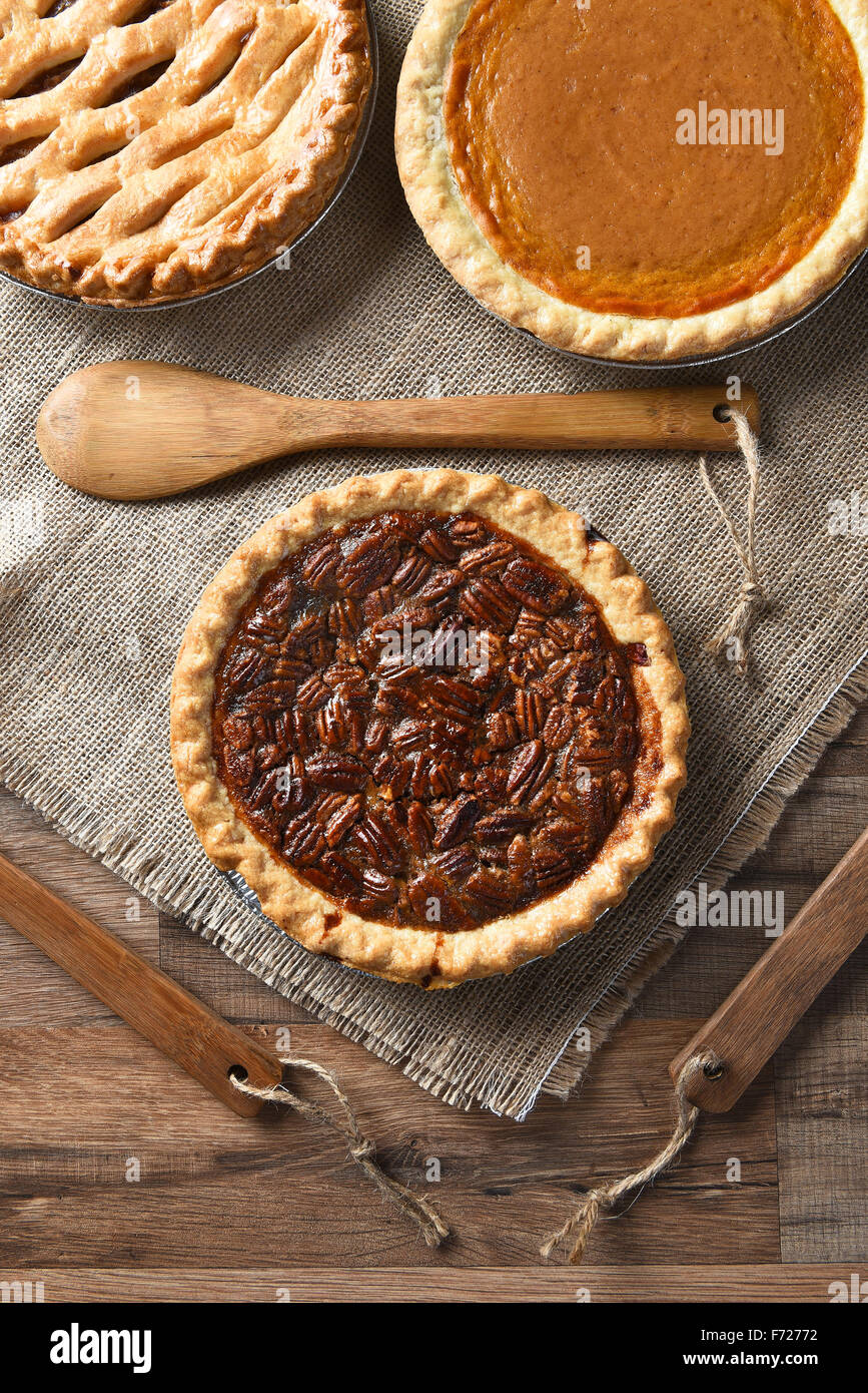 High angle vertical view of three pies for A thanksgiving feast. Pecan in the front with Apple and Pumpkin pies in the back. Stock Photo