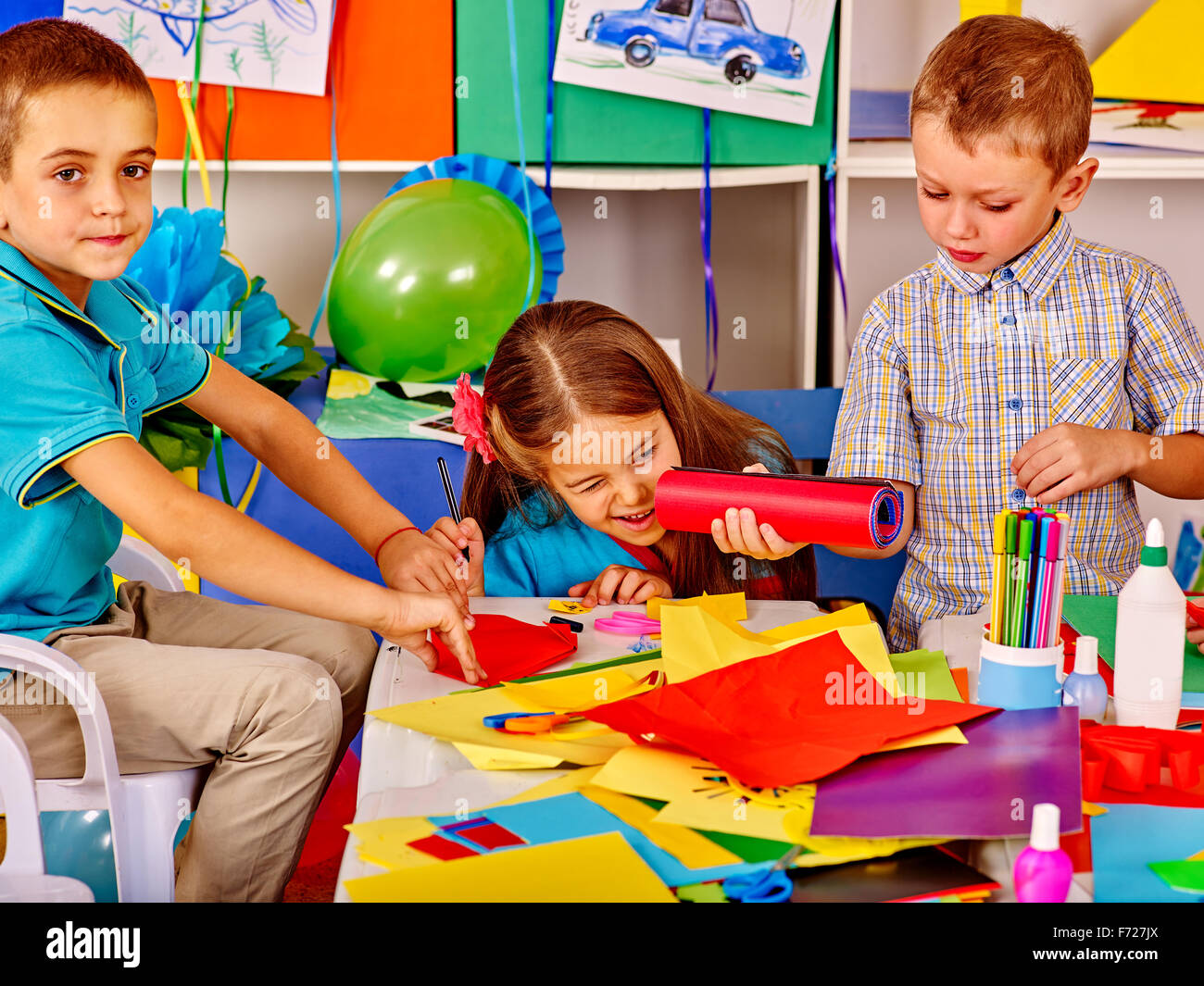 Kids holding colored paper on table in kindergarten Stock Photo - Alamy