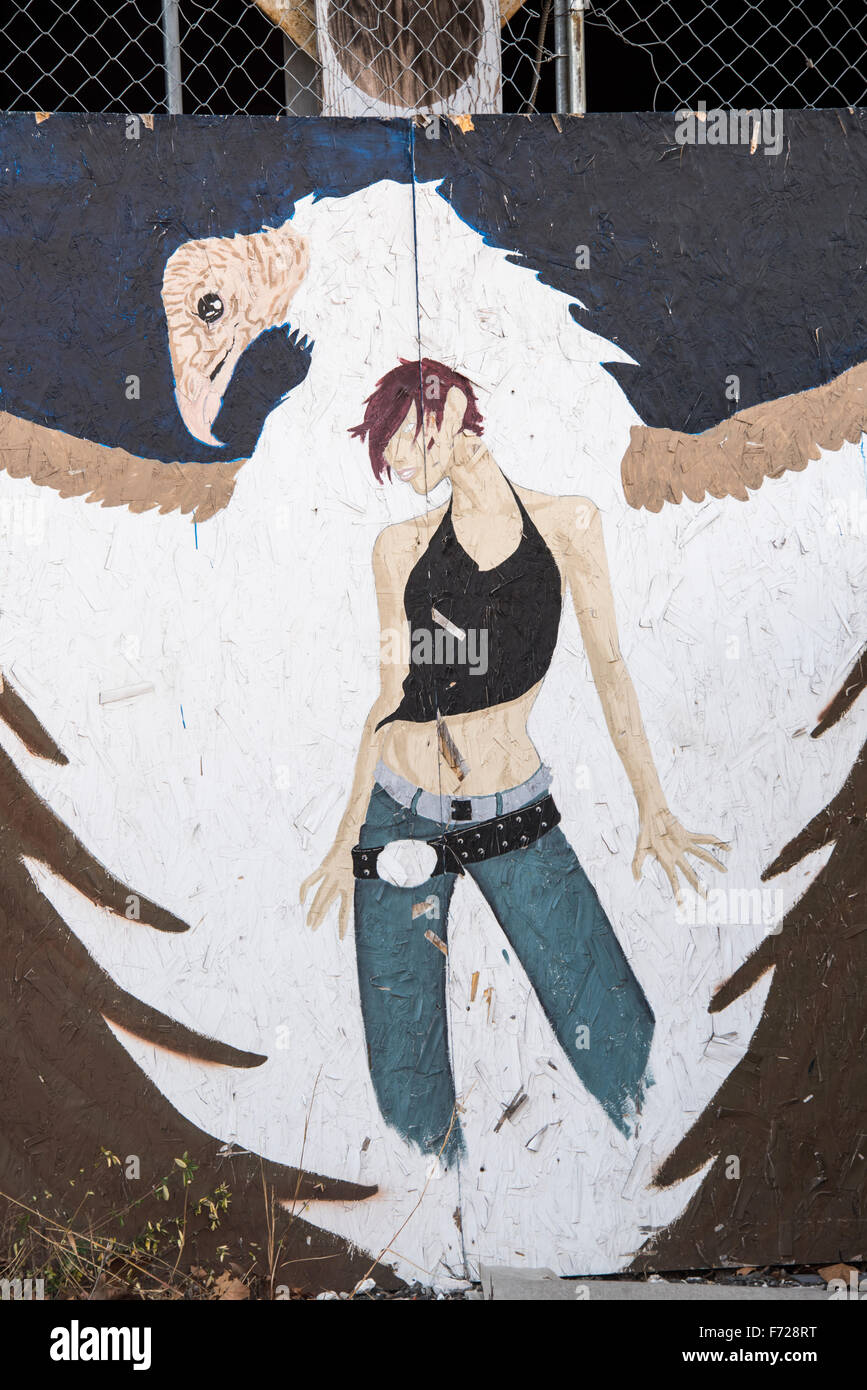 Young Female and bird painting on side of abandon building Stock Photo