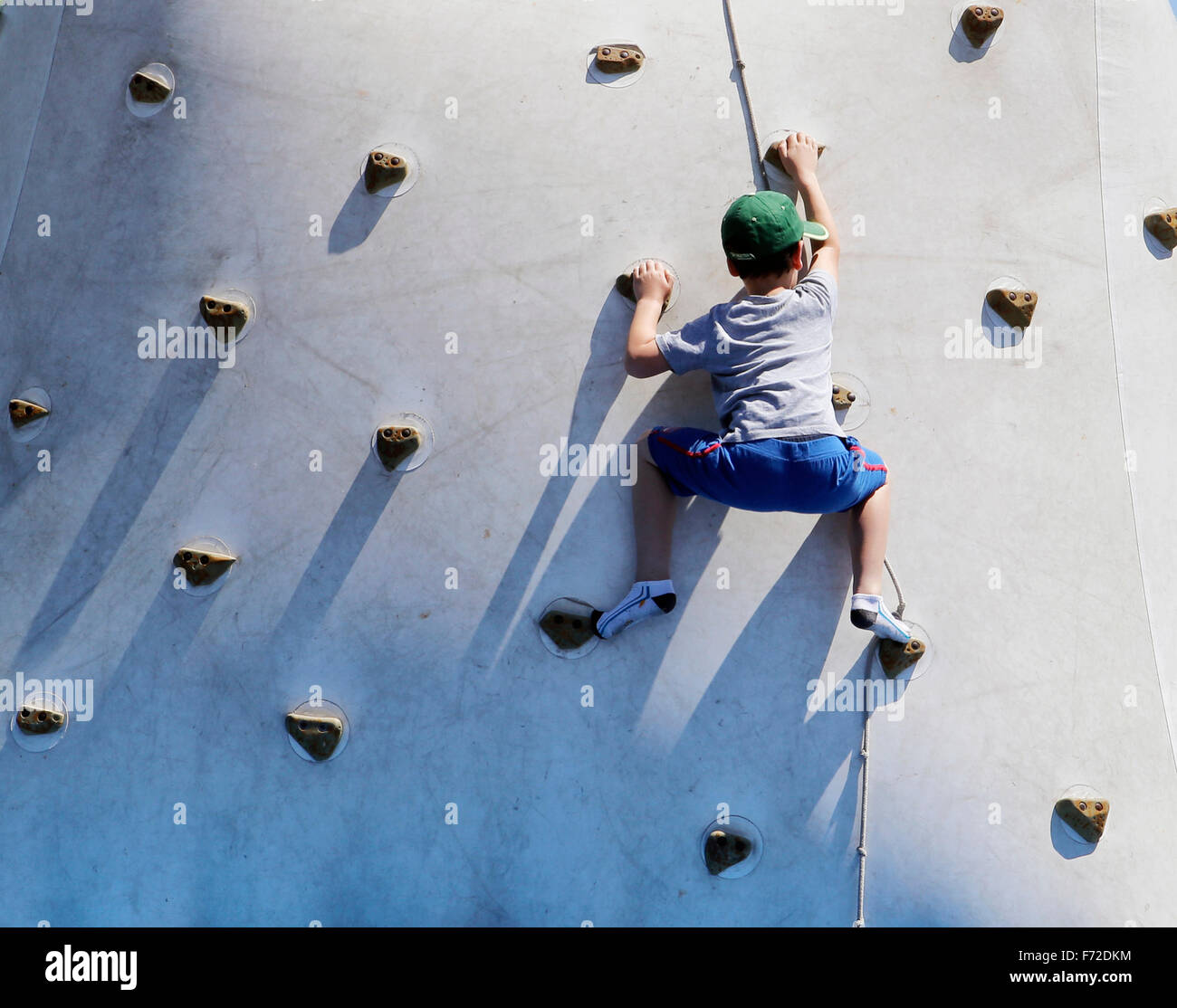 A children learns to climb on a climbing wall during a local youth sports fair. Stock Photo