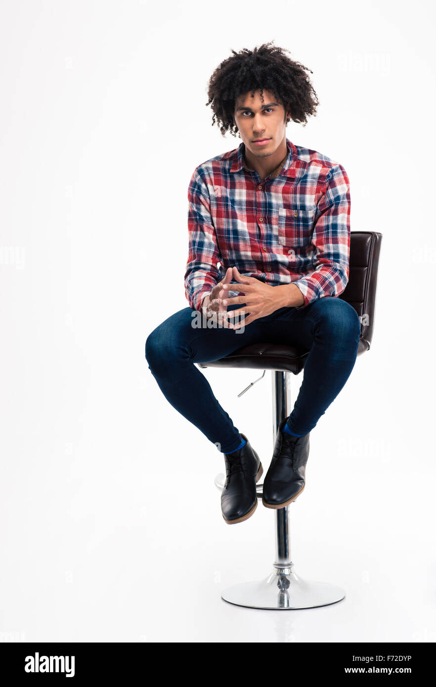 Full length portrait of a young man sitting on the chair isolated on a white background Stock Photo