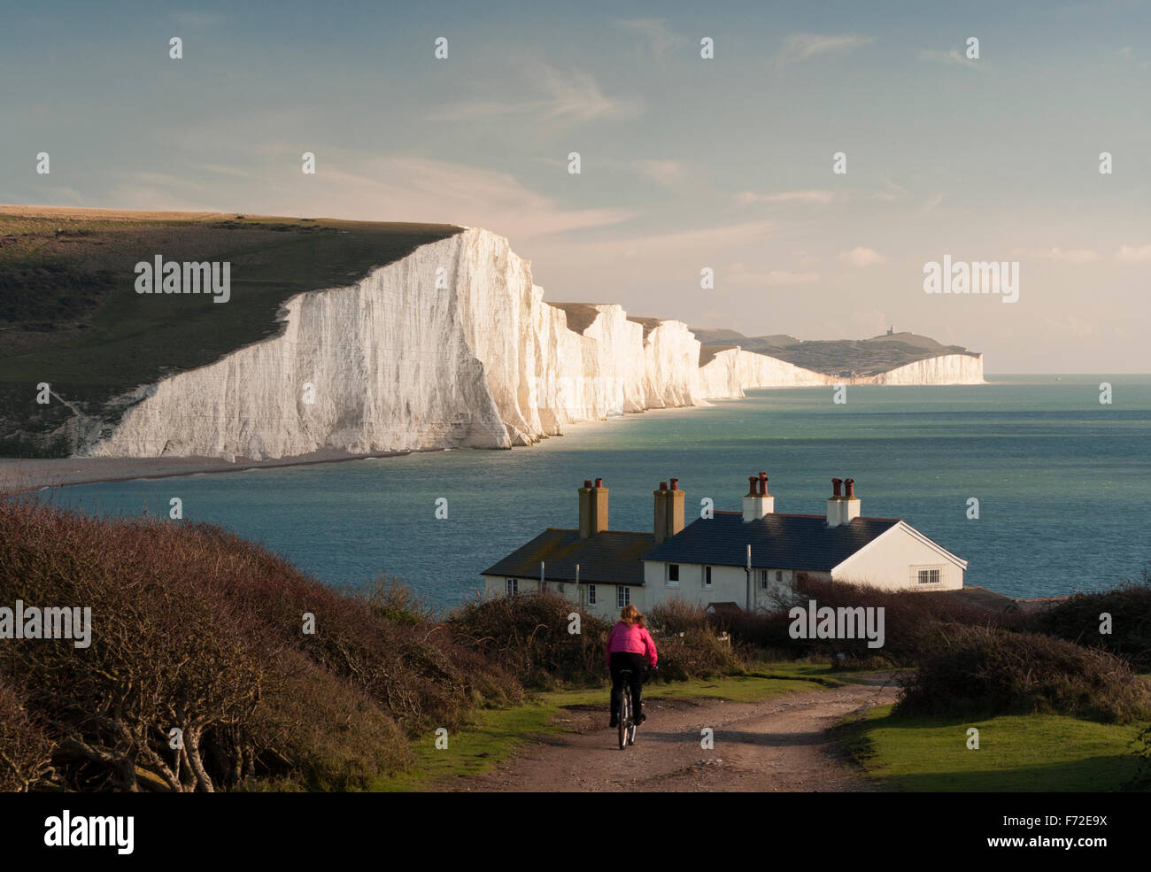 The famous Seven Sisters Cliffs, and Coast Guard Cottages and an unknown cyclist riding down the track, at Seaford Head,EastSussex, UK. Stock Photo
