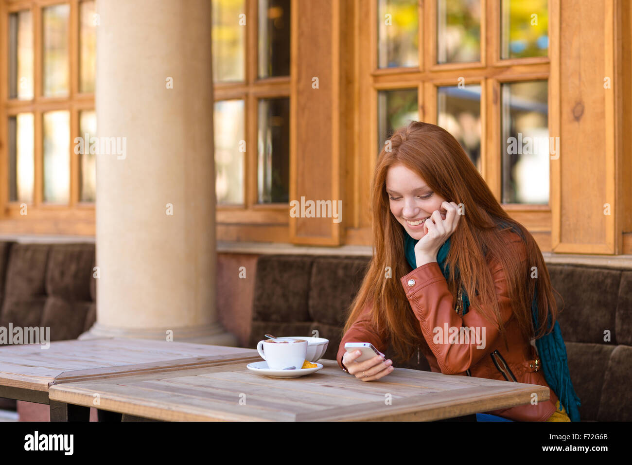 Cute smiling happy young female with beautiful long red hair in lether ...