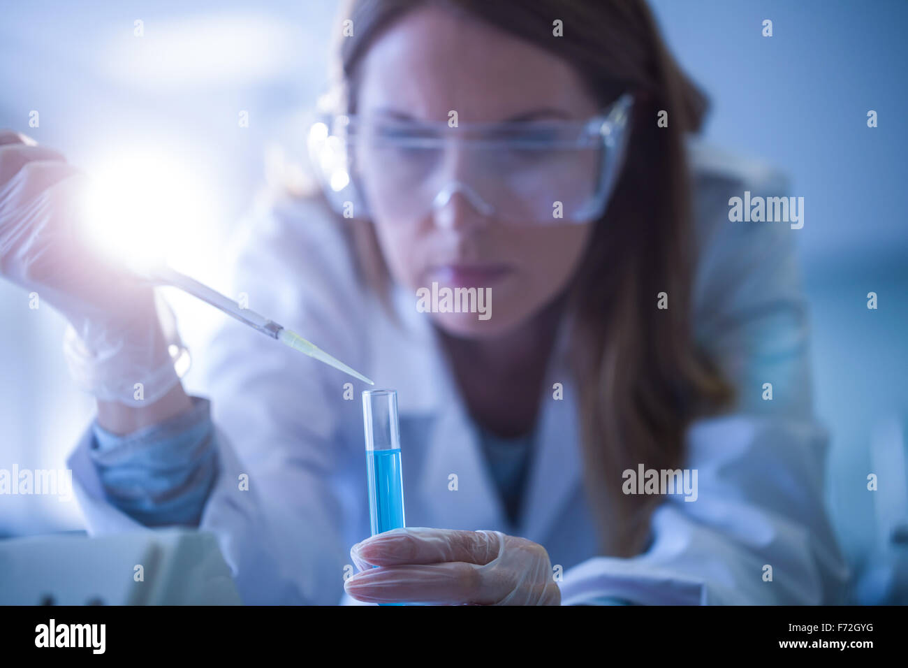 Scientist syringing chemical into test tube Stock Photo