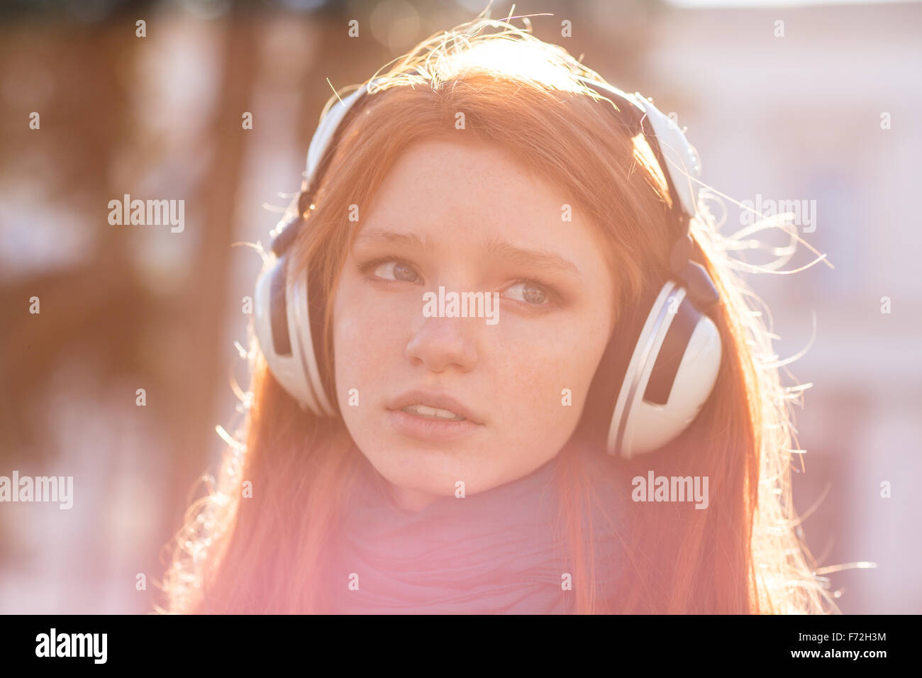 Closeup of thoughtful pretty young lady with long hair in headphones ...