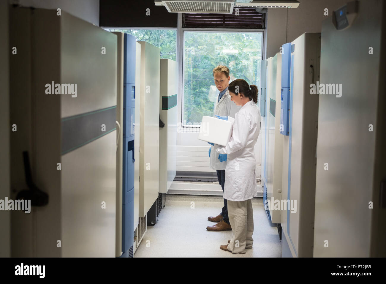 Two scientists beside large fridge unit Stock Photo