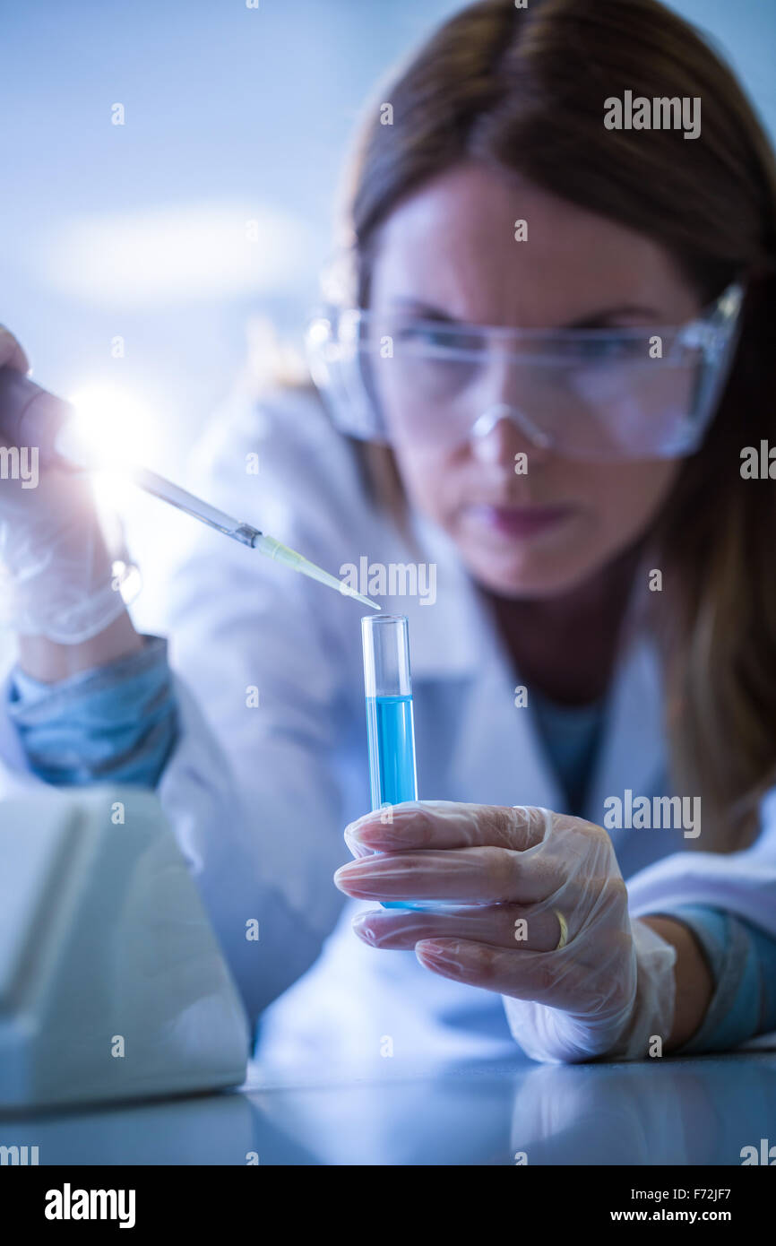 Scientist syringing chemical into test tube Stock Photo