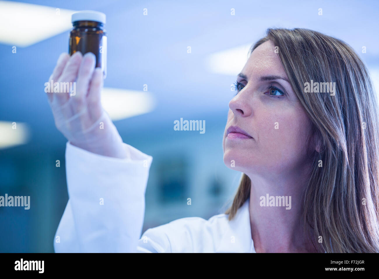 Scientist looking at beaker of chemical Stock Photo