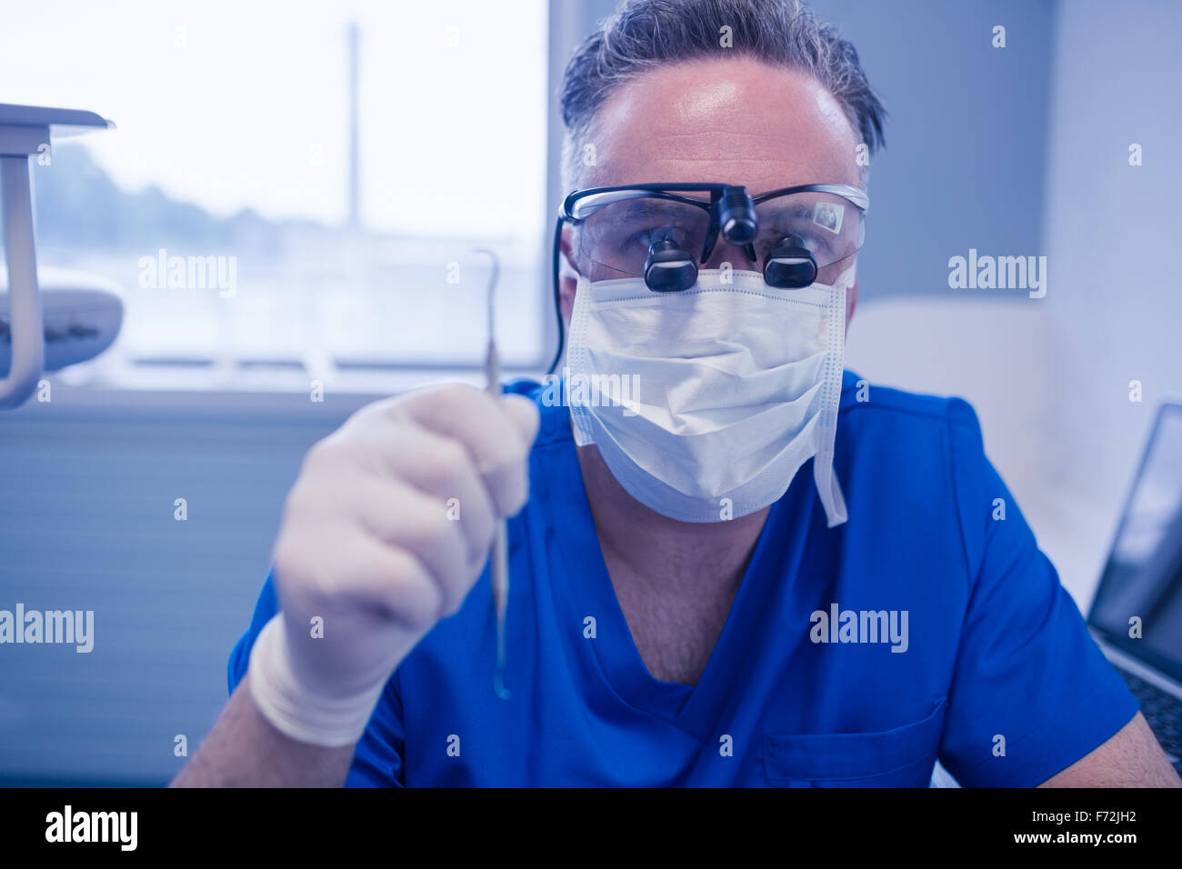 Male dentist with dental loupes holding dental tools Stock Photo Alamy