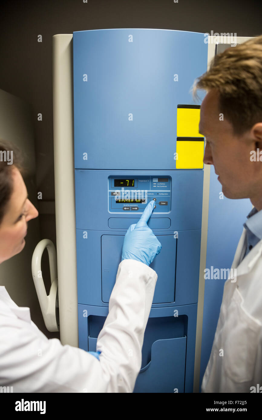 Two scientists changing setting on fridge Stock Photo