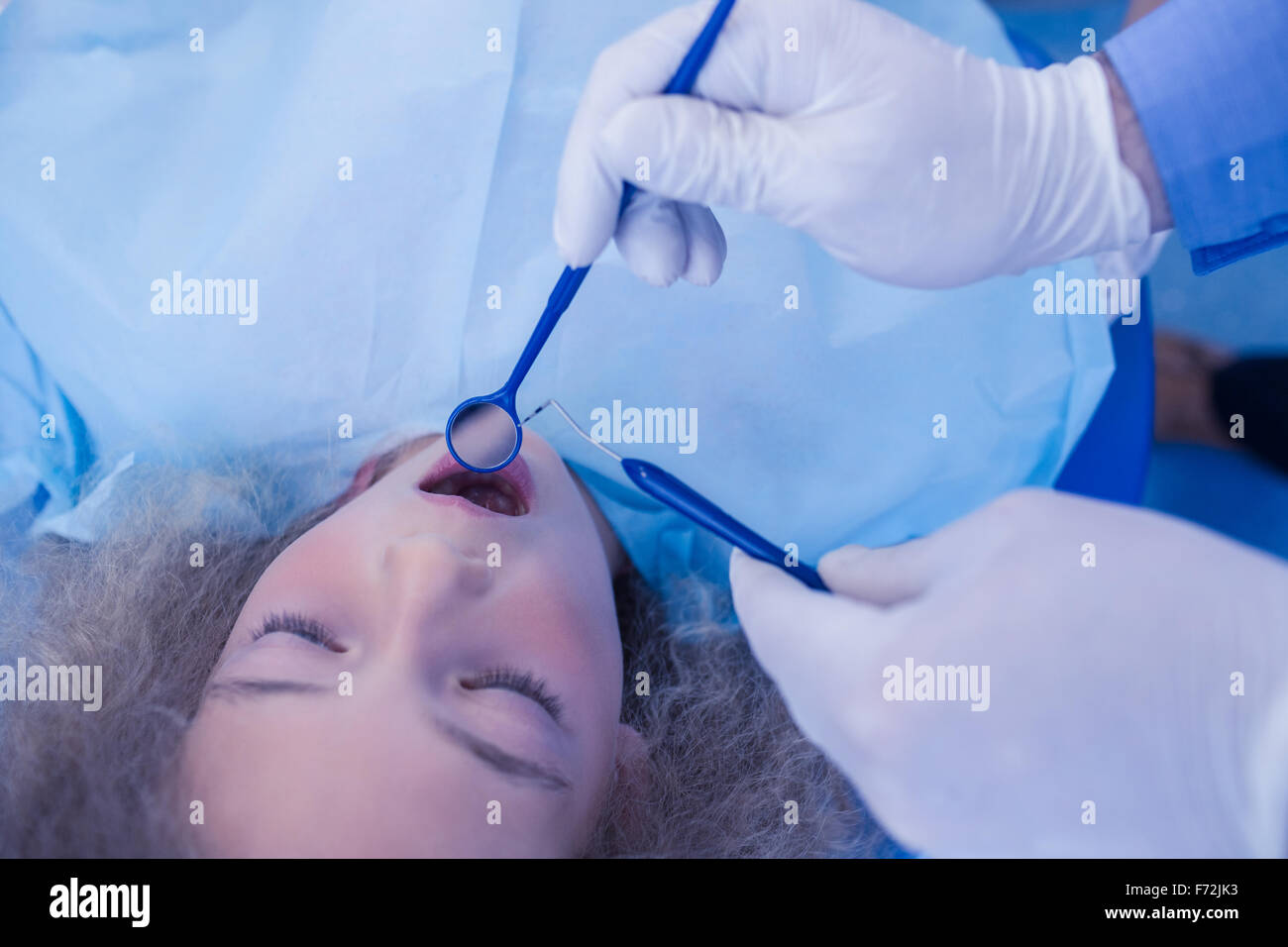 Pediatric dentist using dental explorer and angled mirror Stock Photo