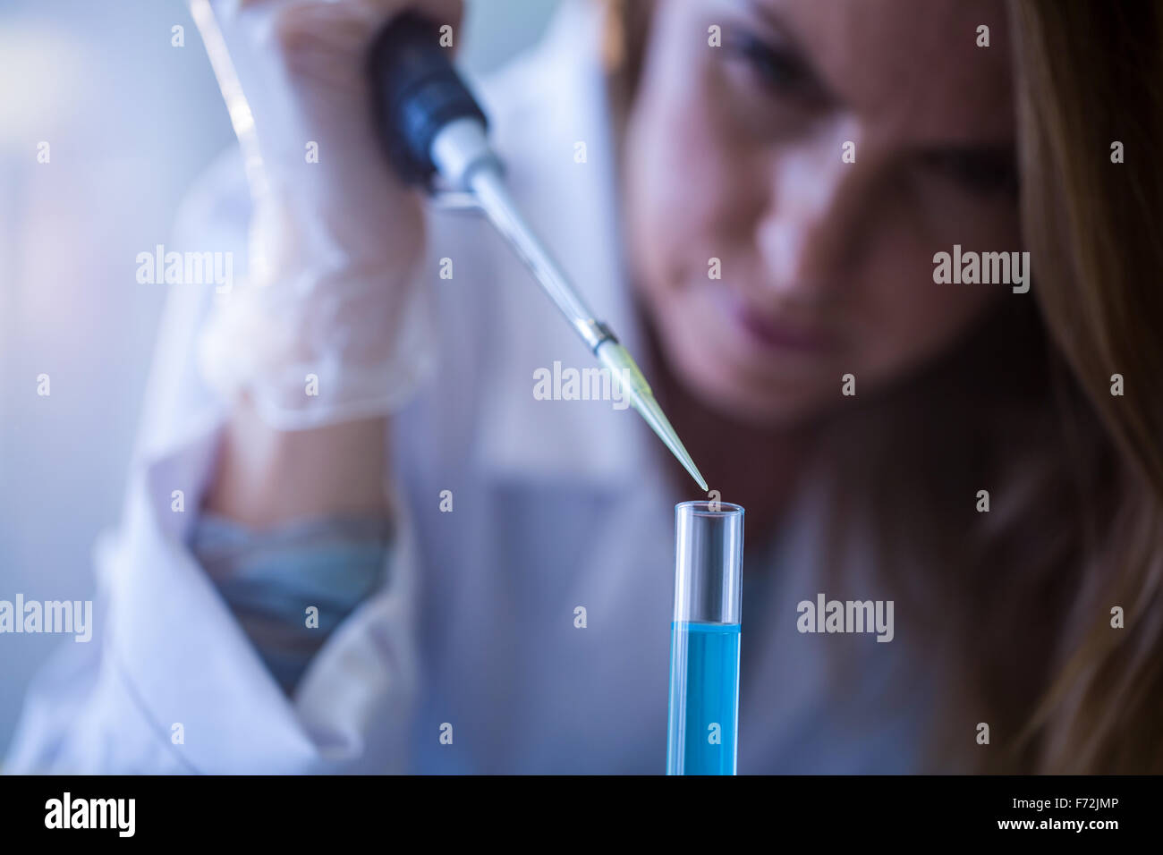 Scientist syringing chemical into test tube Stock Photo