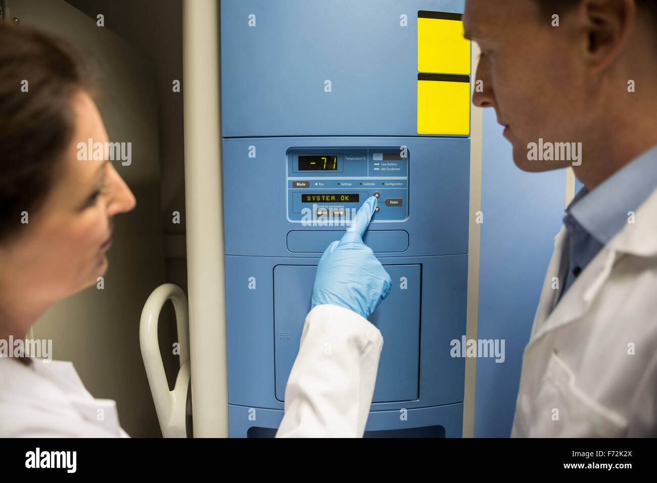 Two scientists changing setting on fridge Stock Photo