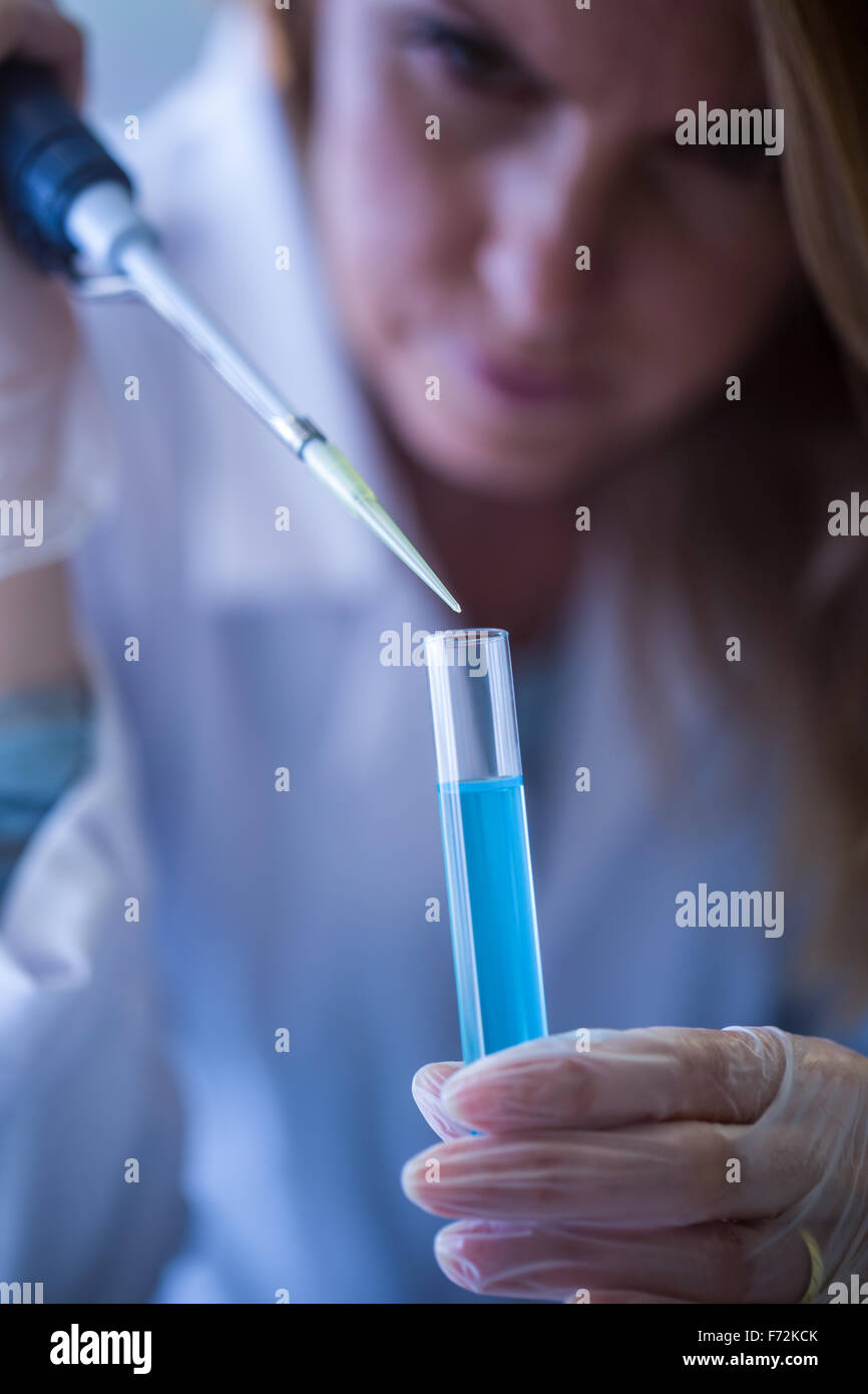 Scientist syringing chemical into test tube Stock Photo