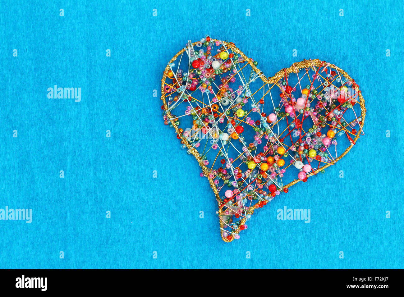 Heart made of colorful beads on blue background with copy space Stock