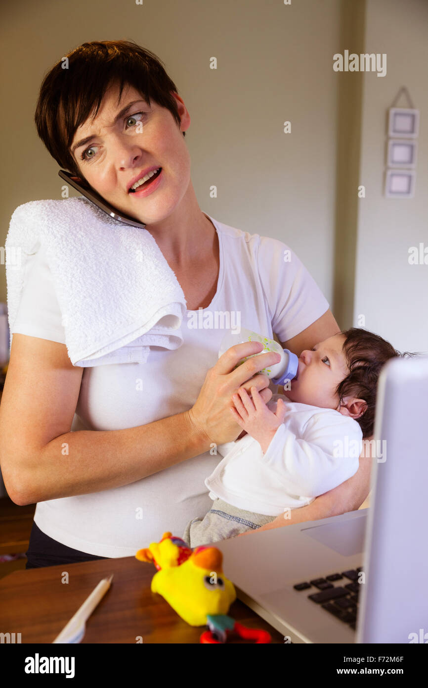 Mother feeding her baby and having phone call Stock Photo