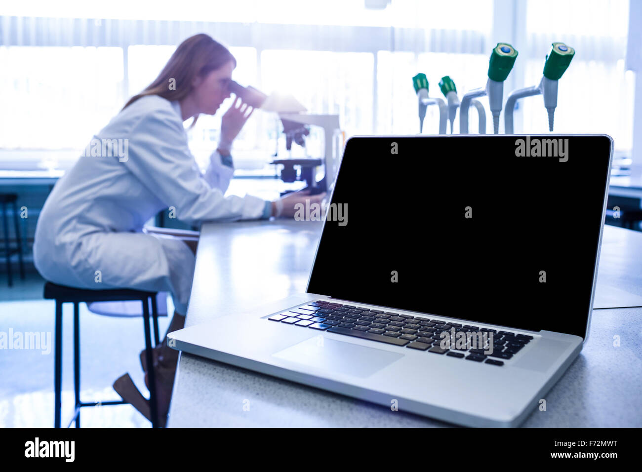 Scientist working with a microscope in laboratory Stock Photo