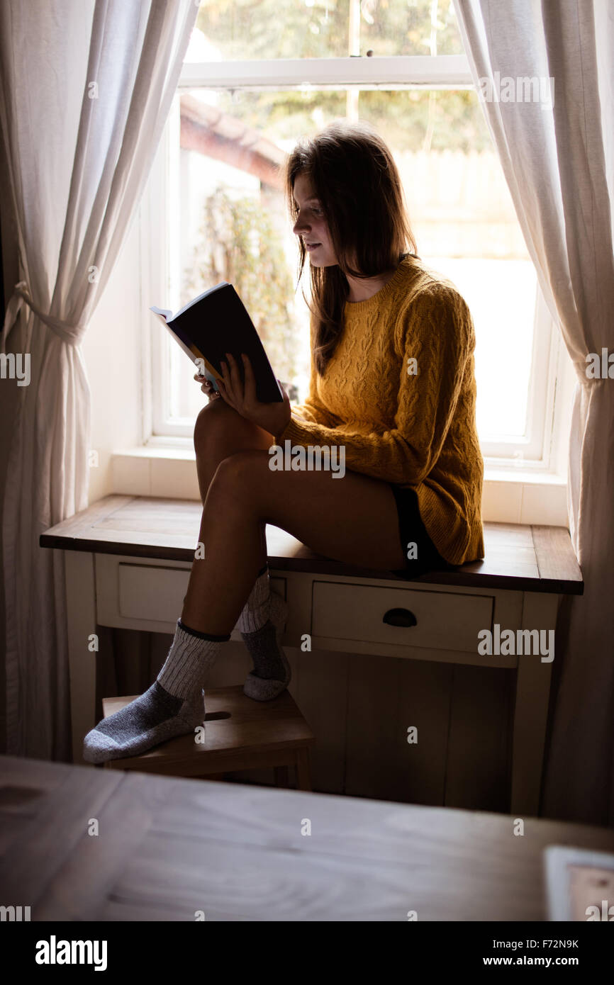 Young woman sitting on table studying Stock Photo - Alamy